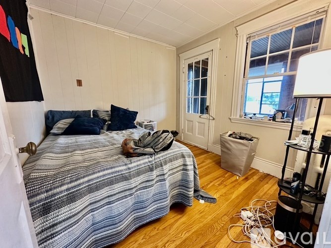 A bedroom with a bed, a nightstand, and a window.