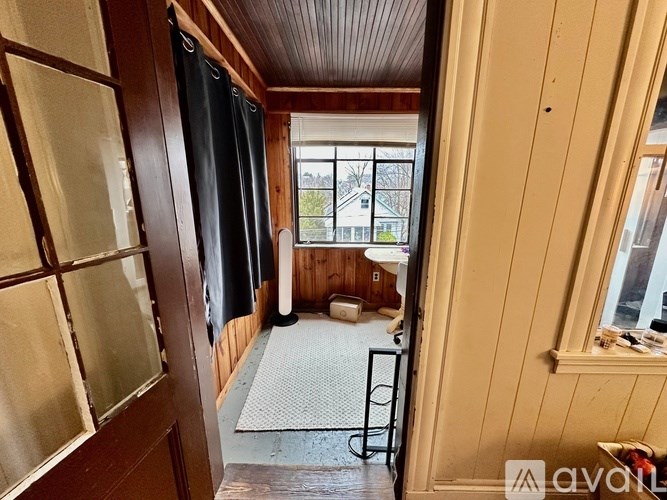 A room with wooden walls and a window overlooking a balcony.