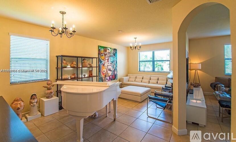 A living room with a white piano and a chandelier.