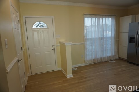 A kitchen area with a white door and a window with curtains.