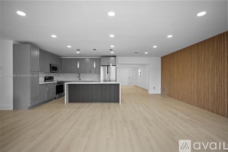 A modern kitchen with wooden flooring and a central island.