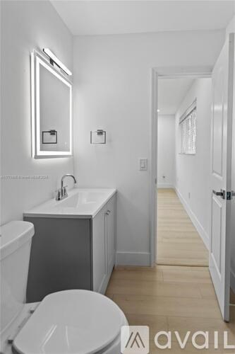 A bathroom with a toilet, sink and mirror.