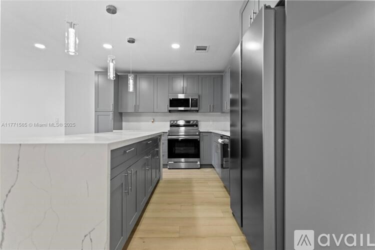 A modern kitchen with a marble countertop and stainless steel appliances.