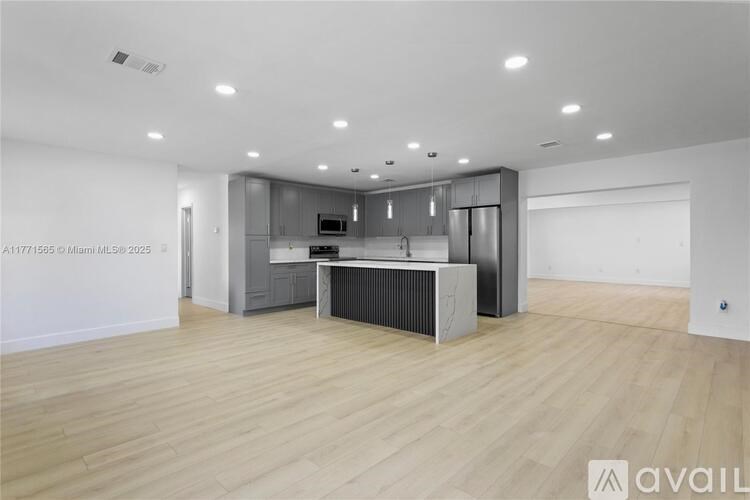 A spacious kitchen with wooden flooring and modern appliances.