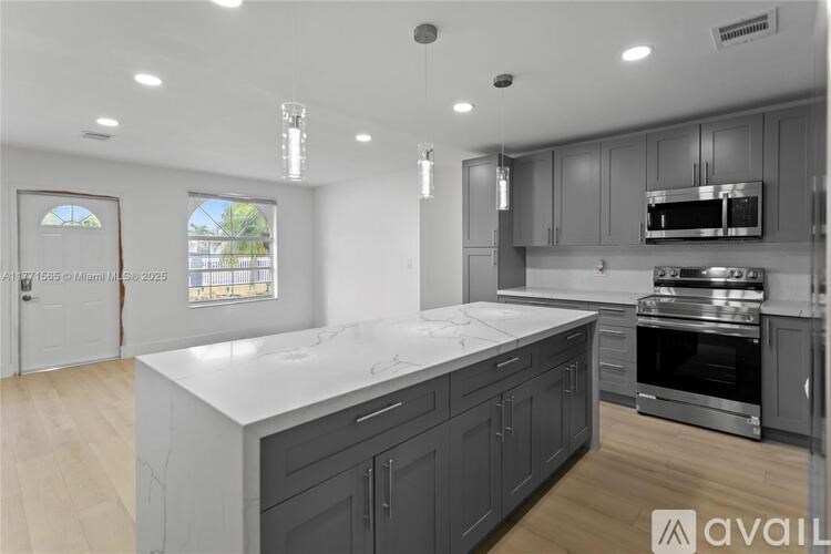 A modern kitchen with dark cabinets and stainless steel appliances.