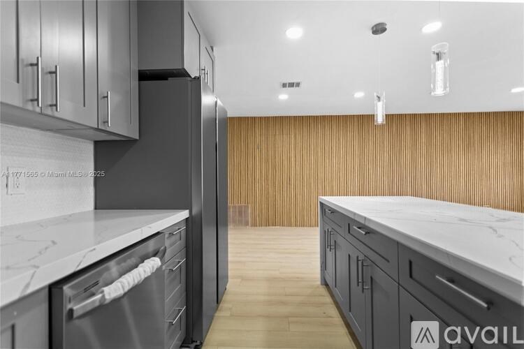A modern kitchen with dark cabinets and a marble countertop.