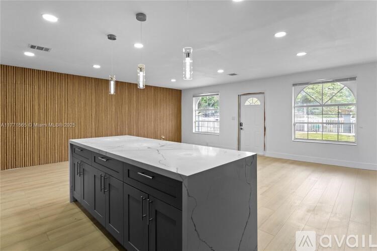 A kitchen with a marble countertop and wooden cabinets.