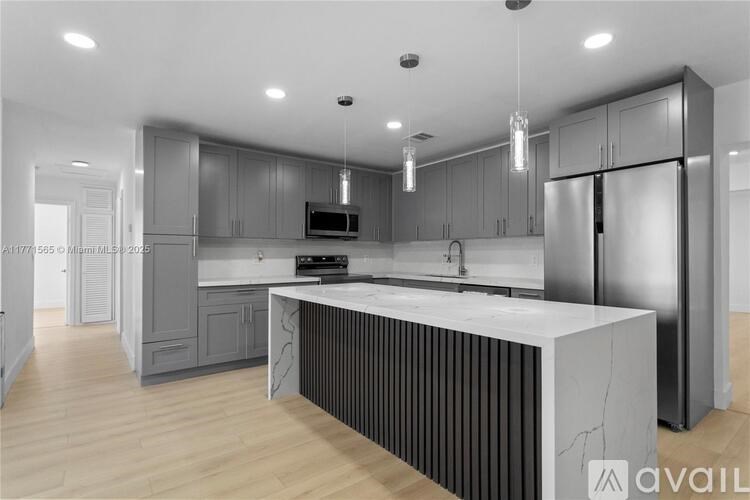 A modern kitchen with a central island and stainless steel appliances.