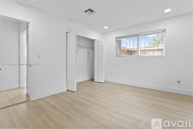 A spacious room with wooden flooring and white walls.