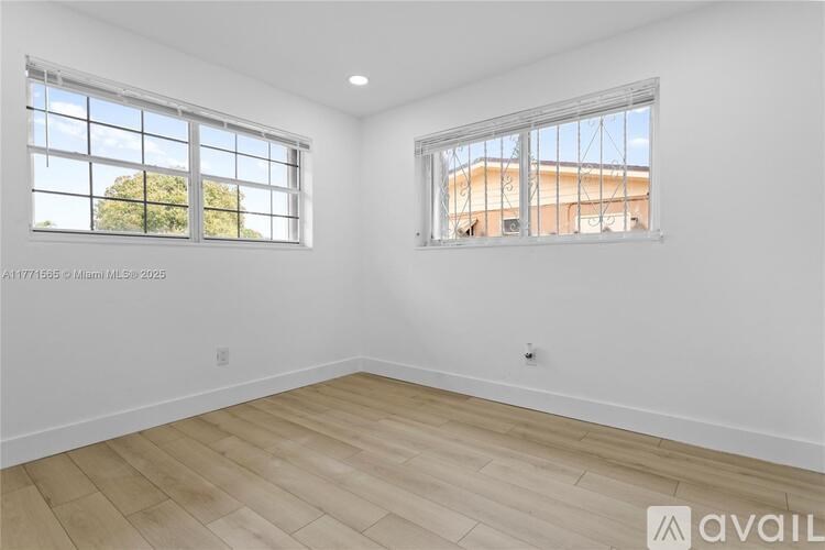 A room with two windows and wooden flooring is available for rent.