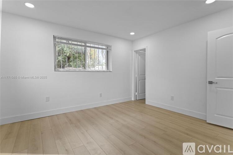 A spacious room with wooden flooring and white walls.