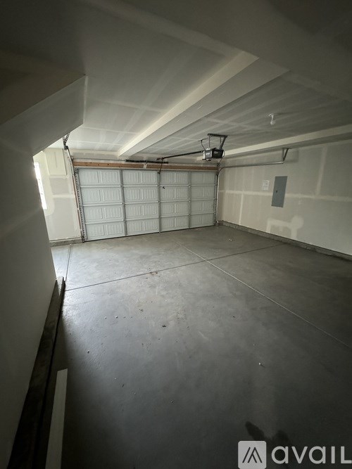 A spacious garage with a basketball hoop and a closed white door.