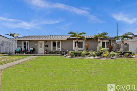A house with a lawn in front and a blue sky above.