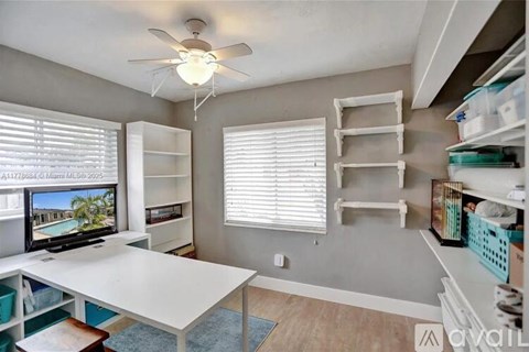 A room with a white table, a television, and a ceiling fan.