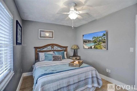 A bedroom with a bed, a ceiling fan, and a picture of a pool.