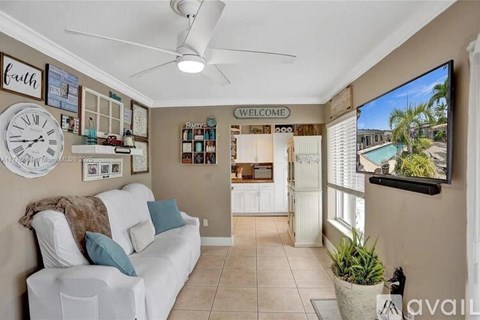 A living room with a white couch and a flat screen TV on the wall.