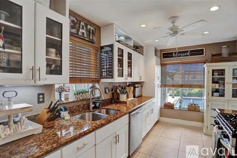 A kitchen with granite countertops and white cabinets.