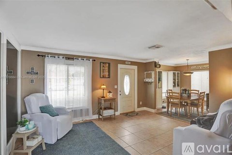 A living room with a white chair and a dining table.