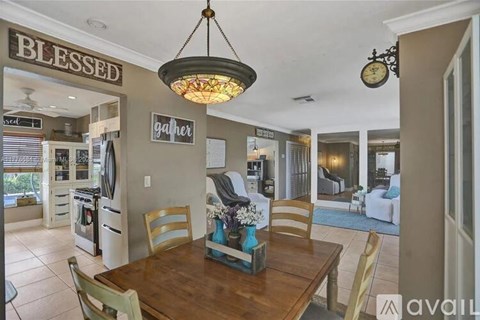 A dining room with a wooden table and chairs, a chandelier, and a sign that says "BLESSED".