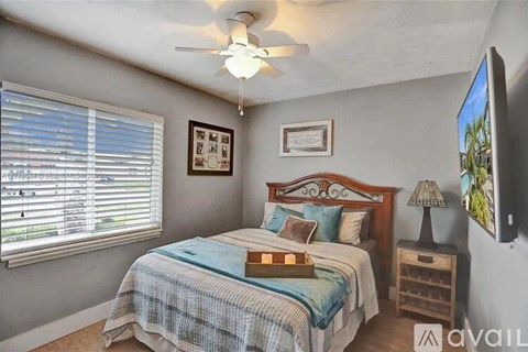 A bedroom with a bed, nightstand, and window with blinds.