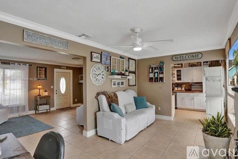 A living room with a white couch and a clock on the wall.