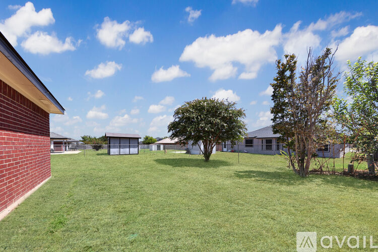A grassy field with a tree and a building in the background.