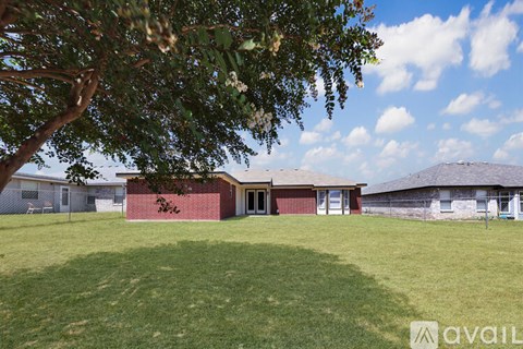 A house with a red brick wall and a tree in the foreground.