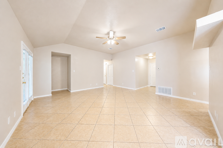 A spacious room with beige tiled flooring and white walls.