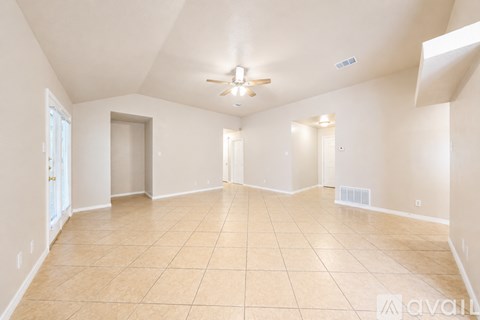 A spacious room with beige tiled flooring and white walls.
