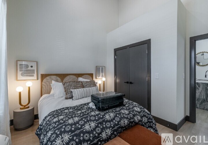 A bedroom with a bed covered in a black and white patterned duvet.