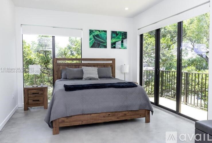 A bedroom with a large bed and a view of trees through the sliding glass doors.