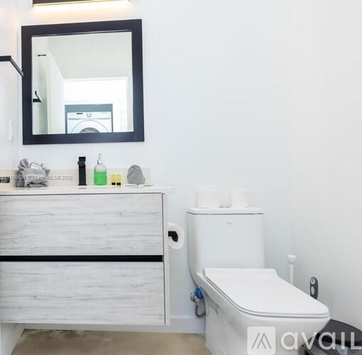 A white toilet sits next to a wooden cabinet with a mirror above it.