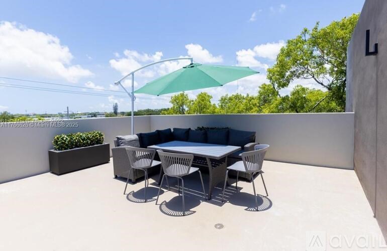 A patio with a table and chairs under a green umbrella.