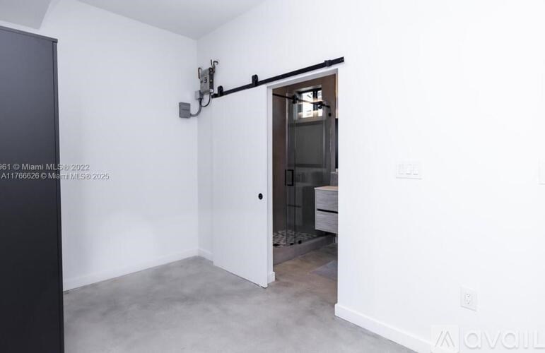 A room with a white wall and a door leading to another room.