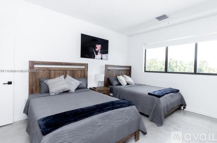 A bedroom with two beds and a flat screen TV mounted on the wall.