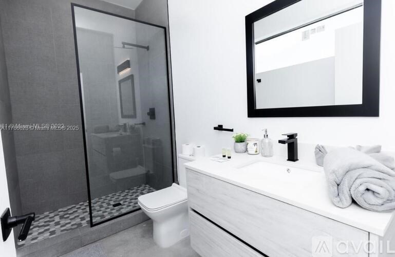 A modern bathroom with a toilet, sink, and mirror.