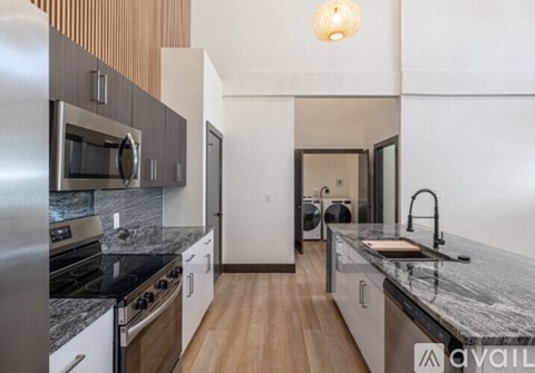 A modern kitchen with a granite countertop and stainless steel appliances.