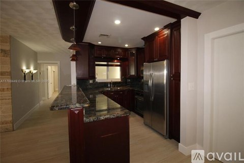 A kitchen with dark wood cabinets and a granite countertop.