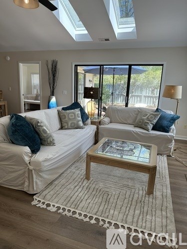 A living room with a white couch and a glass table.