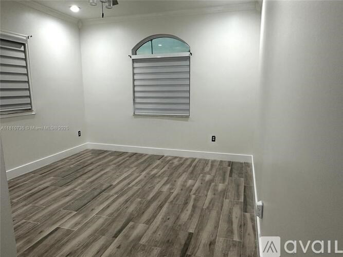 A room with wooden flooring and a window with blinds.