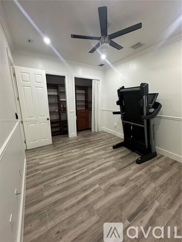 A room with a ceiling fan and a black entertainment center.
