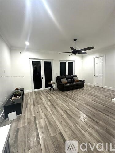A living room with a black couch and a ceiling fan.