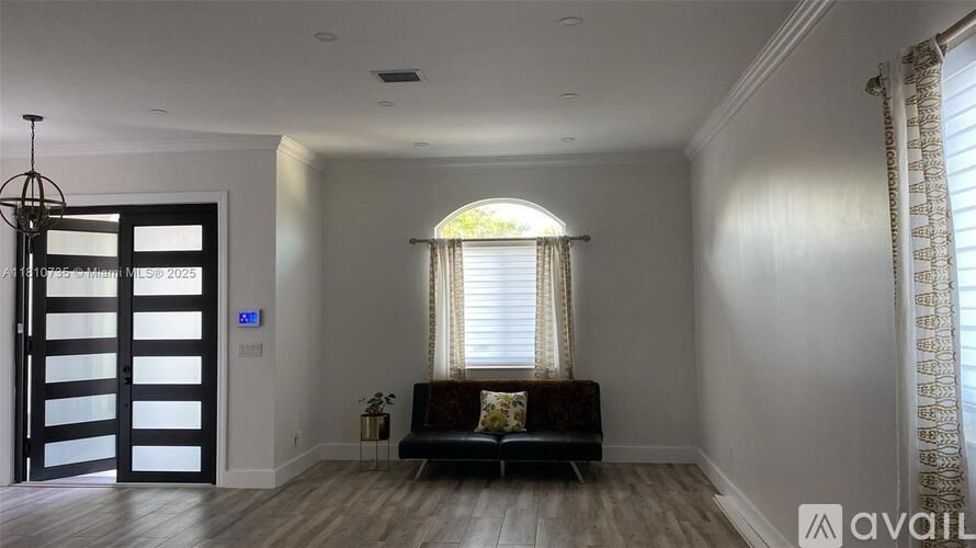 A modern living room with a black couch and a window with curtains.