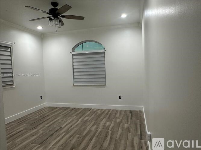 A room with a ceiling fan and a window with blinds.