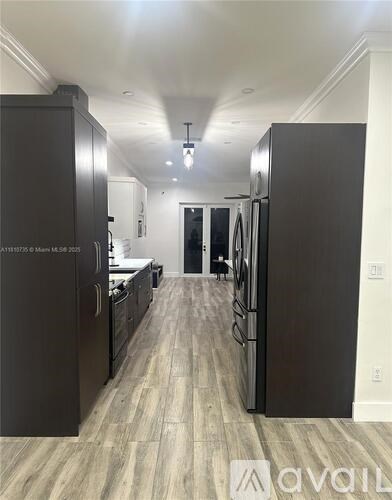 A modern kitchen with dark wood cabinets and a refrigerator.