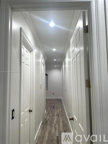 A hallway with white walls and a light on the ceiling.