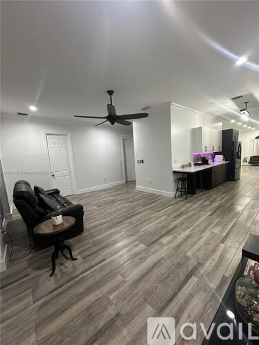 A room with a ceiling fan and a chair with a table.