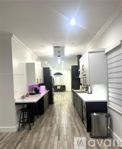 A kitchen with a white counter top and wooden flooring.