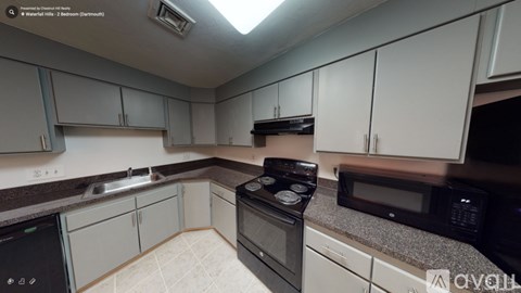 A kitchen with a black stove top oven, a black microwave, and white cabinets.