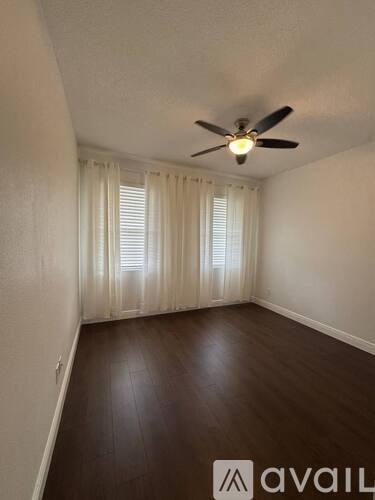 A room with a ceiling fan and wooden flooring.